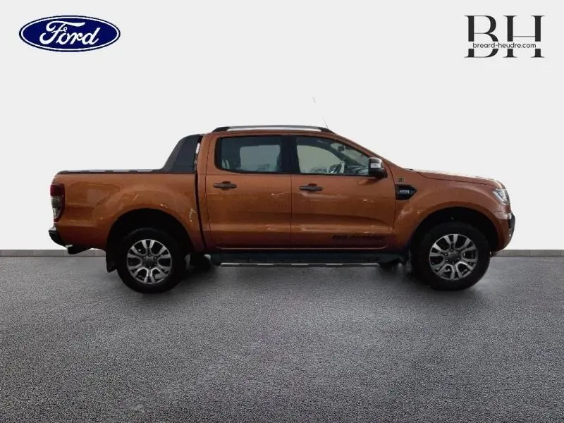 Vue latérale droite d'un Ford Ranger Wildtrak 2017 en Pride Orange métallisée avec double cabine et rideau de plateau rigide.