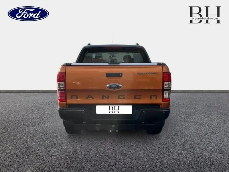 Vue arrière du Ford Ranger Wildtrak 2017 en Pride Orange métallisée avec hayon marqué Ranger et attelage visible.