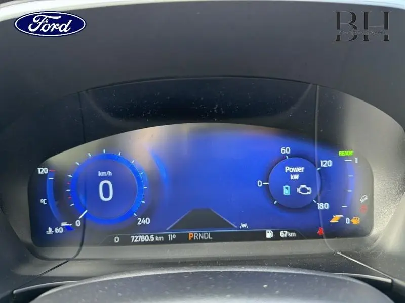 Vue rapprochée du tableau de bord numérique bleu du Ford Kuga 2022 affichant la vitesse à 0 km/h et les indicateurs hybrides.