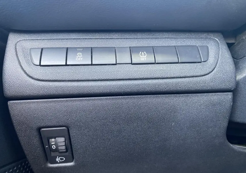 Gros plan sur les boutons de contrôle du tableau de bord de la Peugeot 208 gris foncé, avec réglage de stabilité et pression pneus.