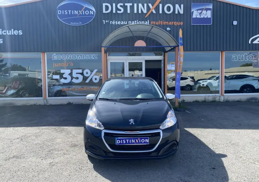 Peugeot 208 gris foncé vue de face, stationnée devant un showroom avec enseigne Distinxion.
