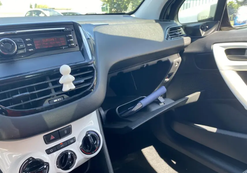 Vue intérieure côté passager de la Peugeot 208 gris foncé 2018, avec boîte à gants ouverte et tableau de bord blanc.