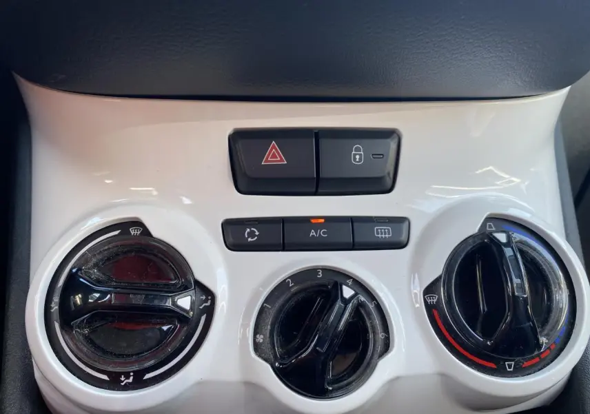 Gros plan sur la console centrale blanche du Peugeot 208 2018, avec commandes de climatisation et boutons de sécurité.