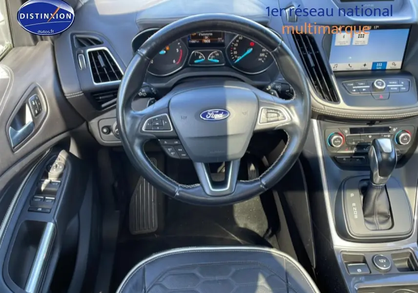 Vue intérieure centrée sur le volant cuir multifonction et la console centrale du Ford Kuga blanc 2017 avec boîte auto.