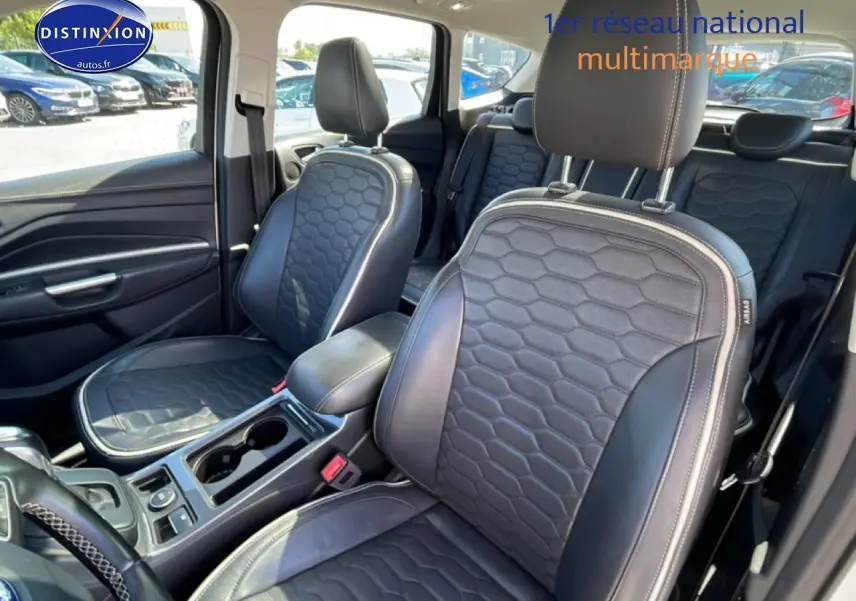Vue intérieure côté avant droit du Ford Kuga 2017 avec sièges en cuir noir à motif hexagonal et accoudoir central.