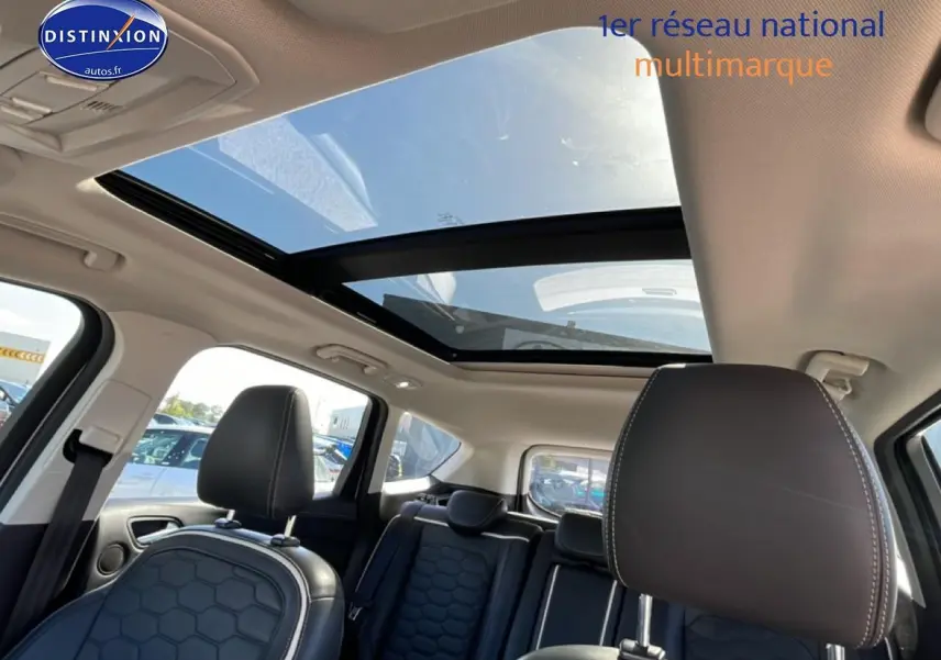 Vue intérieure du Ford Kuga blanc 2017 montrant les sièges avant en cuir et le toit ouvrant panoramique en verre.