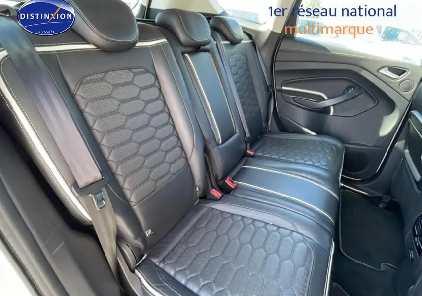 Vue intérieure en 3/4 arrière droit montrant la banquette arrière en cuir noir avec surpiqûres blanches du Ford Kuga blanc.
