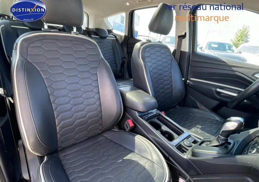 Vue intérieure côté avant droit du Ford Kuga blanc 2017, sièges sport noirs avec surpiqûres claires et console centrale visible.