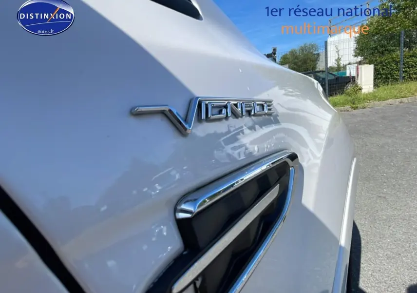 Gros plan sur l'aile avant droite blanche d'un Ford Kuga 2017 avec logo Vignale et prise d'air chromée.