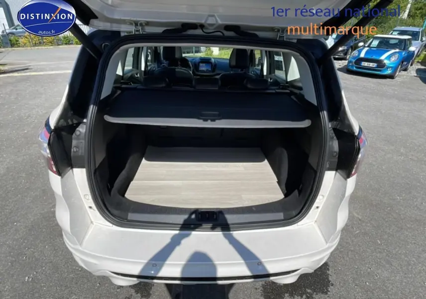 Vue arrière du coffre ouvert d'un Ford Kuga blanc 2017, montrant un espace de chargement propre et un cache-bagages déployé.