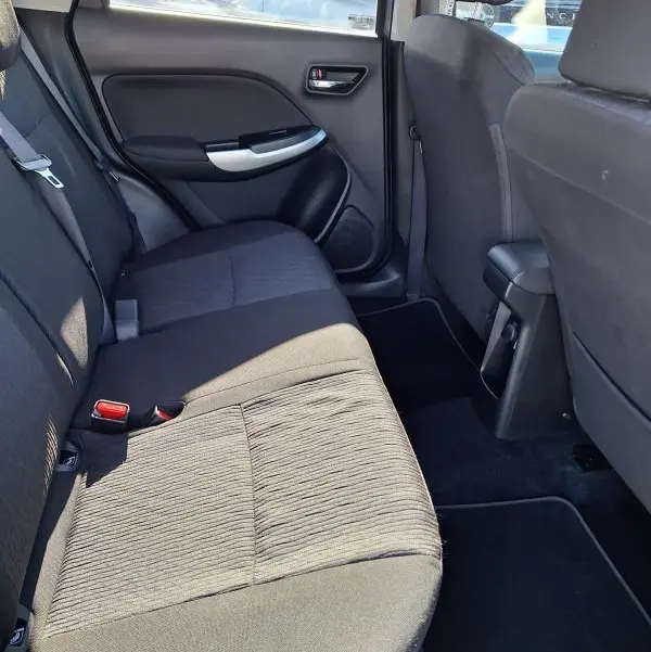 Vue intérieure côté gauche des sièges arrière noirs d'une Suzuki Baleno 2017, montrant la porte et l'habitacle.