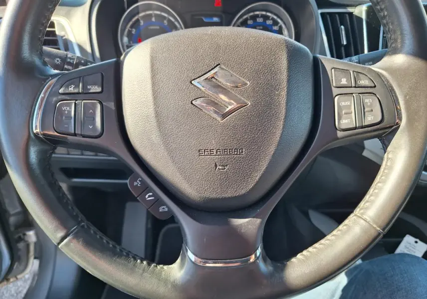 Gros plan sur le volant cuir noir de la Suzuki Baleno 1.0 Boosterjet Pack 2017 avec commandes intégrées.