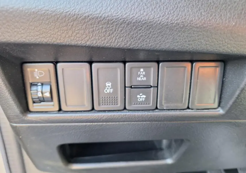 Gros plan sur les boutons de commande noirs du tableau de bord d’une Suzuki Baleno gris clair, version 2017.