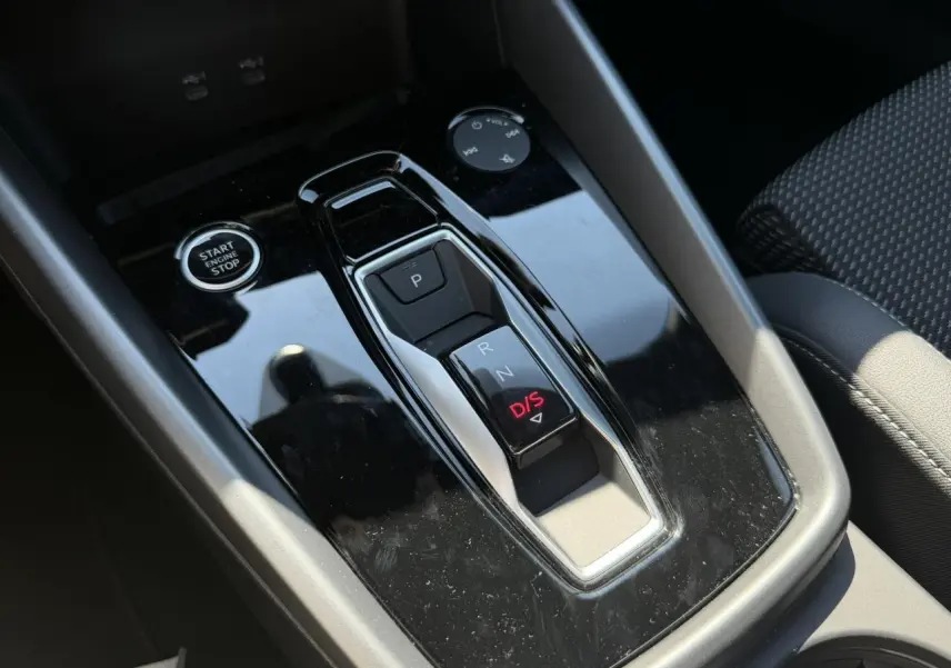 Gros plan sur la console centrale noire brillante avec levier de vitesses automatique et bouton start/stop de l'Audi A3 Sportback 2025.