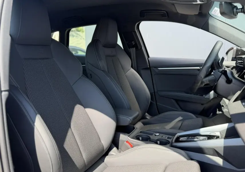 Vue intérieure côté droit de l’Audi A3 Sportback 2025 avec sièges sport noirs et console centrale moderne.