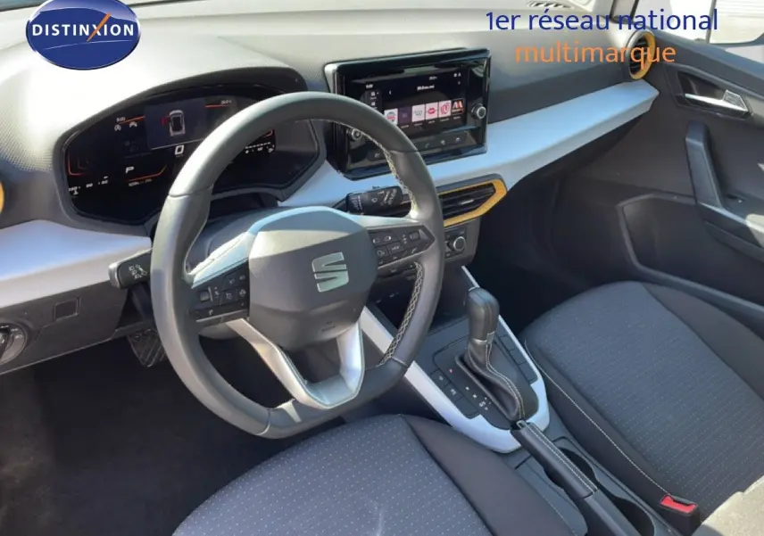 Vue intérieure côté conducteur du SEAT Arona blanc métal avec tableau de bord moderne et volant multifonction noir.