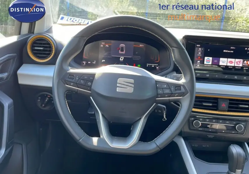 Vue intérieure centrée sur le volant multifonction du SEAT Arona 2025 avec tableau de bord digital et écran tactile.