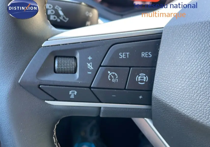 Gros plan sur les commandes au volant du SEAT Arona 2025, volant cuir noir avec boutons de régulateur de vitesse.