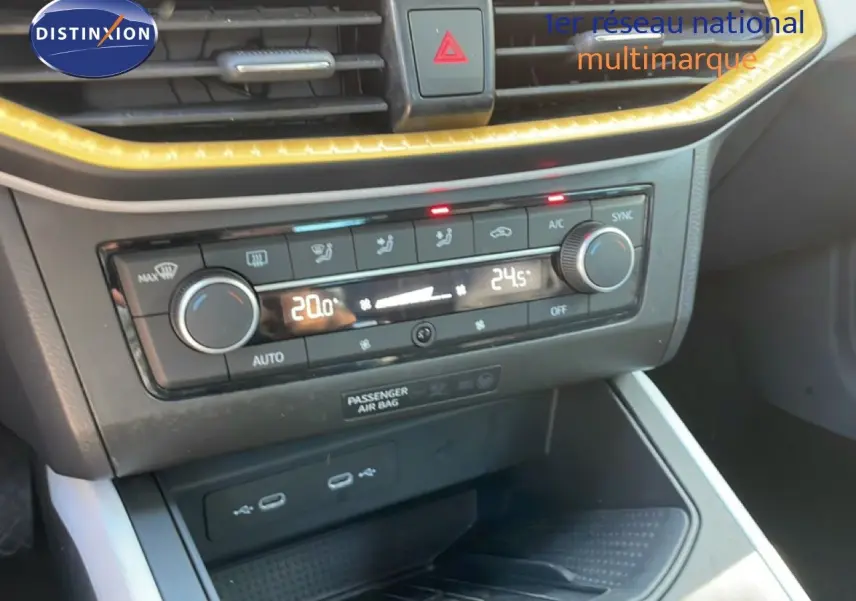 Gros plan sur la console centrale du SEAT Arona 2025, montrant la climatisation bi-zone avec éclairage LED jaune.