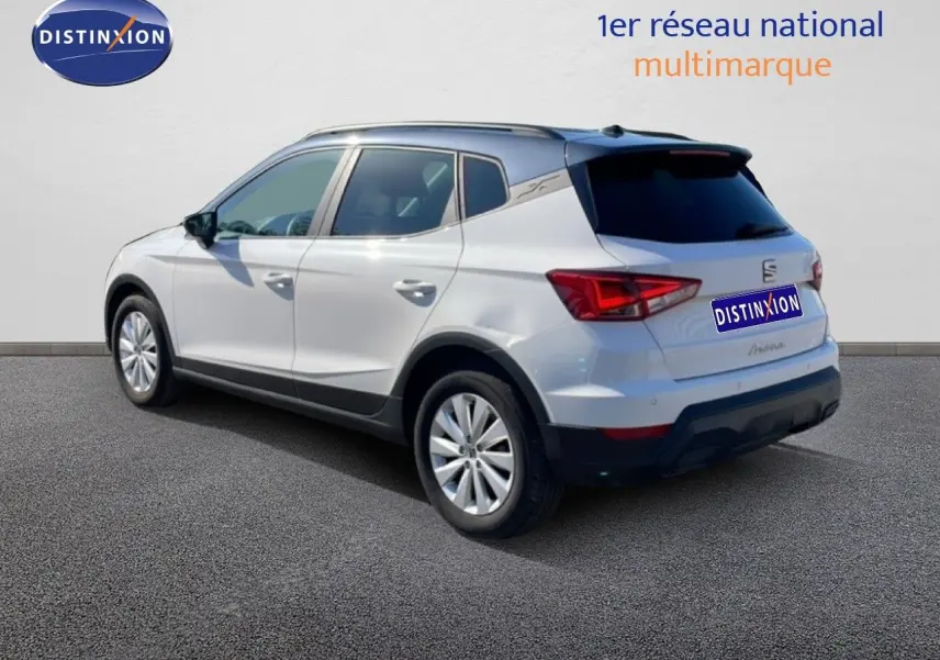 SEAT Arona blanc métal avec toit noir, vue 3/4 arrière côté gauche, sur fond neutre avec logo Distinxion.