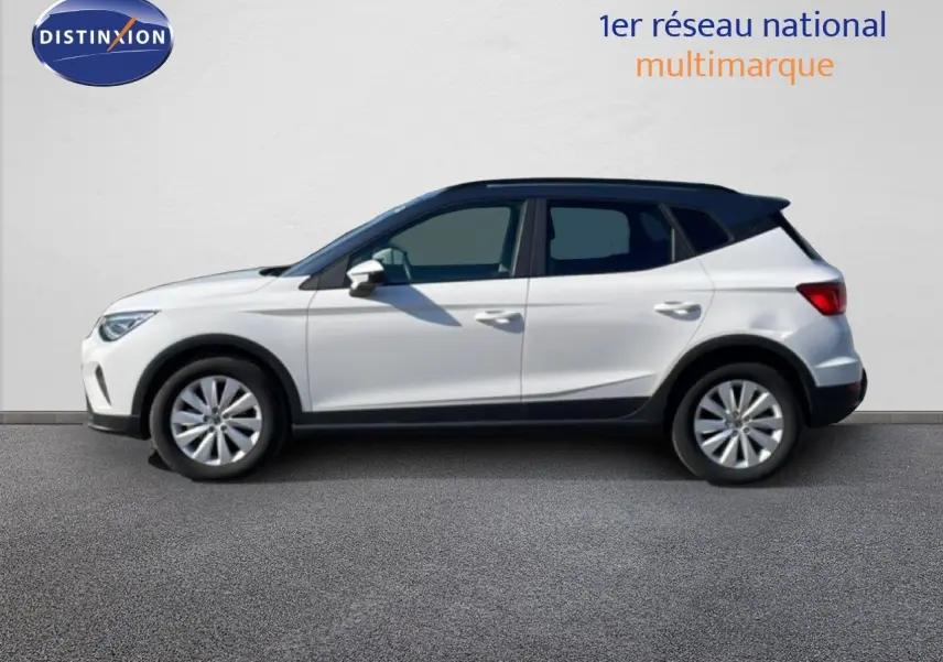 Vue de profil côté gauche d'un SEAT Arona blanc métal avec toit noir, roues alliage et détails noirs sur bas de caisse.