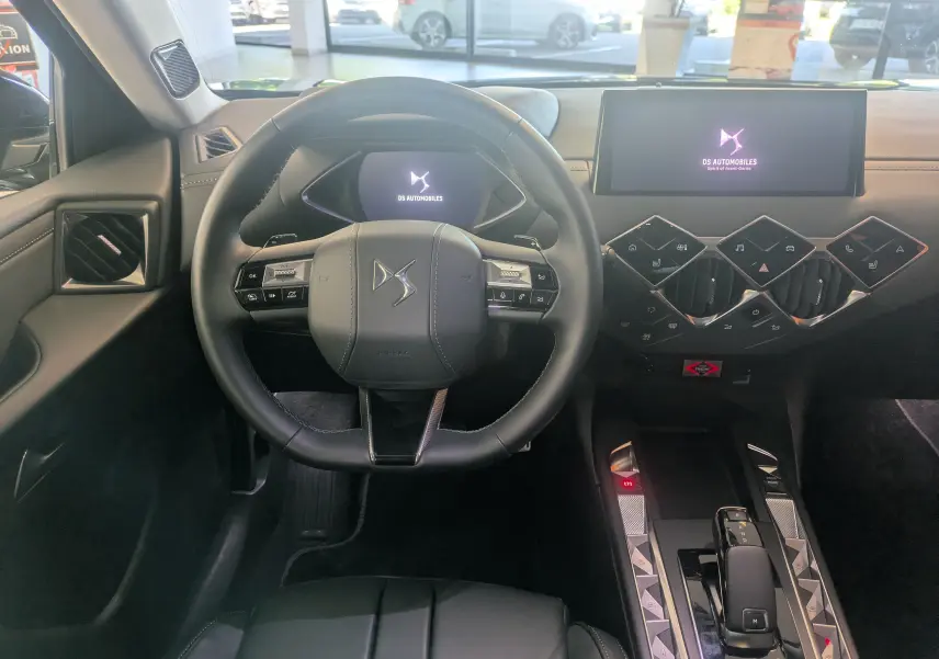 Vue intérieure avant du DS3 2024 noir, volant cuir, tableau de bord digital et console centrale moderne avec écran tactile.