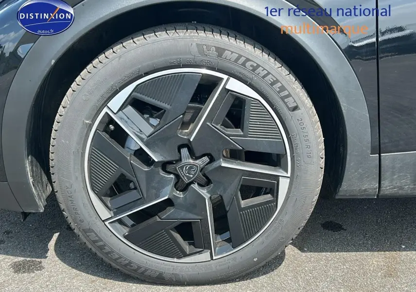 Gros plan sur la jante alu noire au design géométrique du côté avant gauche d'une Peugeot 408 Hybrid 145 GT noire.