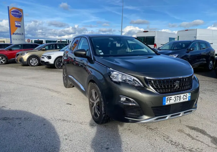 Peugeot 3008 gris foncé vue 3/4 avant droit, avec jantes alliage bi-ton et calandre noire brillante.