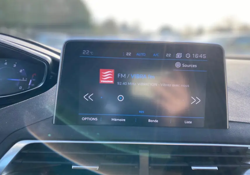Écran tactile central du Peugeot 3008 gris foncé de 2019 affichant la radio FM VIBRA fm en intérieur du tableau de bord.