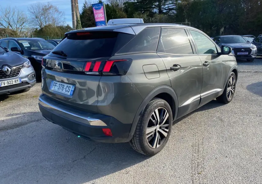 Peugeot 3008 gris foncé vue 3/4 arrière droit, jantes alliage bi-ton et vitres arrière surteintées visibles.