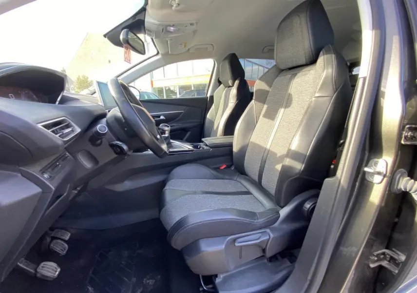 Vue intérieure côté conducteur du Peugeot 3008 gris foncé de 2019, montrant les sièges avant et le tableau de bord.