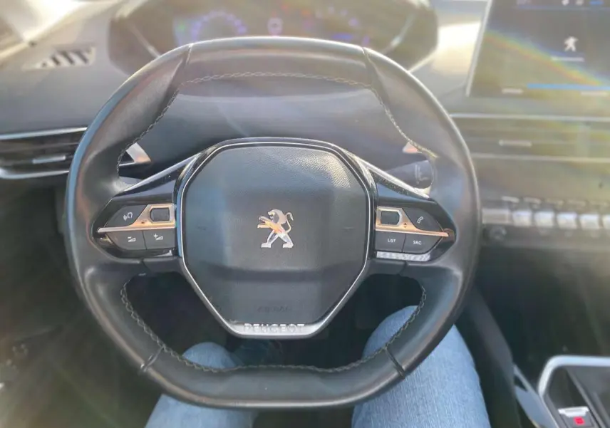 Volant cuir noir du Peugeot 3008 2019 vu de face, avec commandes intégrées et logo lion central argenté.