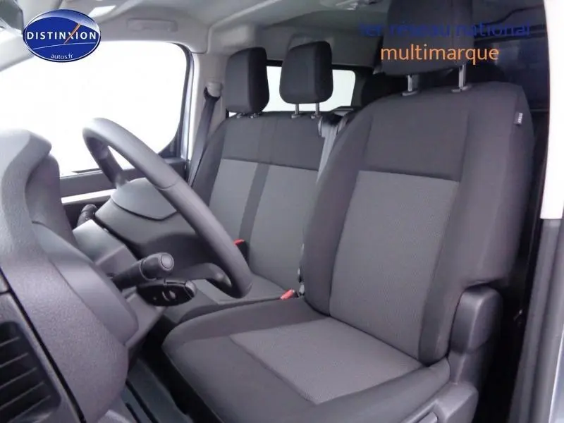 Vue intérieure côté conducteur du Peugeot Expert Fourgon XL 2023, sièges tissu bi-ton noir et gris, volant réglable.