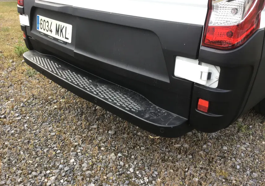 Gros plan sur le pare-chocs arrière noir du fourgon Iveco Daily blanc, avec la plaque d'immatriculation visible côté droit.