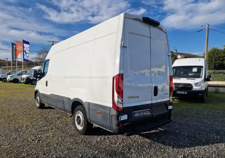 Vue 3/4 arrière d’un Iveco Daily Fourgon blanc 2023 avec portes arrière battantes et pare-chocs noir sur un terrain extérieur.