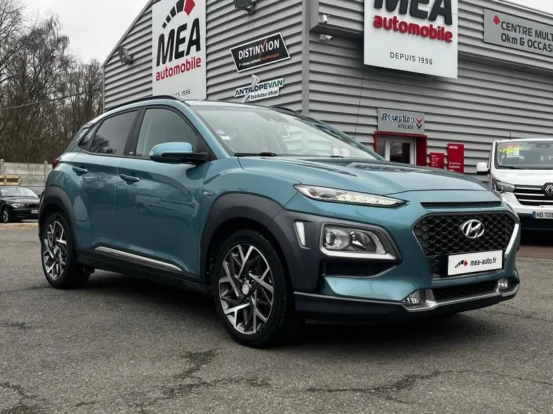 Hyundai Kona 1.6 GDi hybrid bleu en 3/4 avant droit, avec calandre noire et jantes alu distinctives.