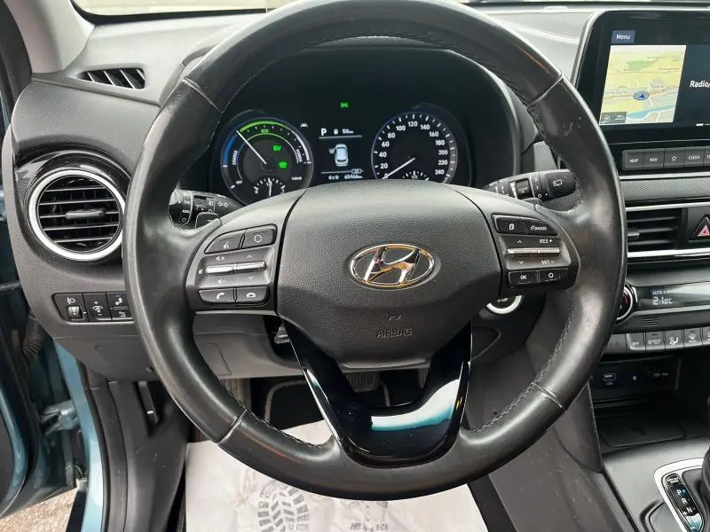 Vue intérieure centrée sur le volant cuir multifonction d'une Hyundai Kona bleu avec tableau de bord digital et écran tactile.
