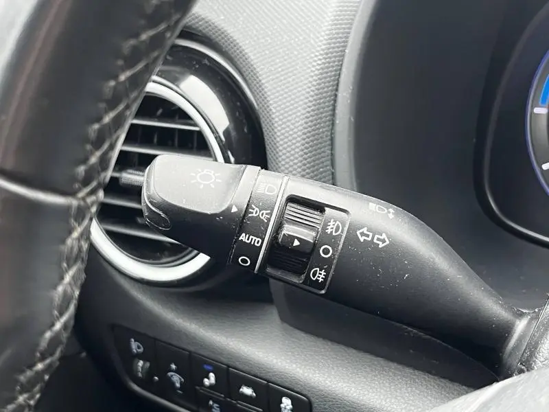 Gros plan sur la commande des feux et clignotants à gauche du volant dans l’habitacle noir du Hyundai Kona bleu 2020.