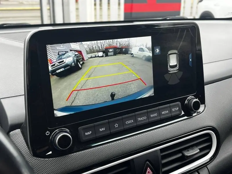 Écran tactile intérieur montrant la caméra de recul du Hyundai Kona bleu, vue arrière avec lignes de guidage colorées.