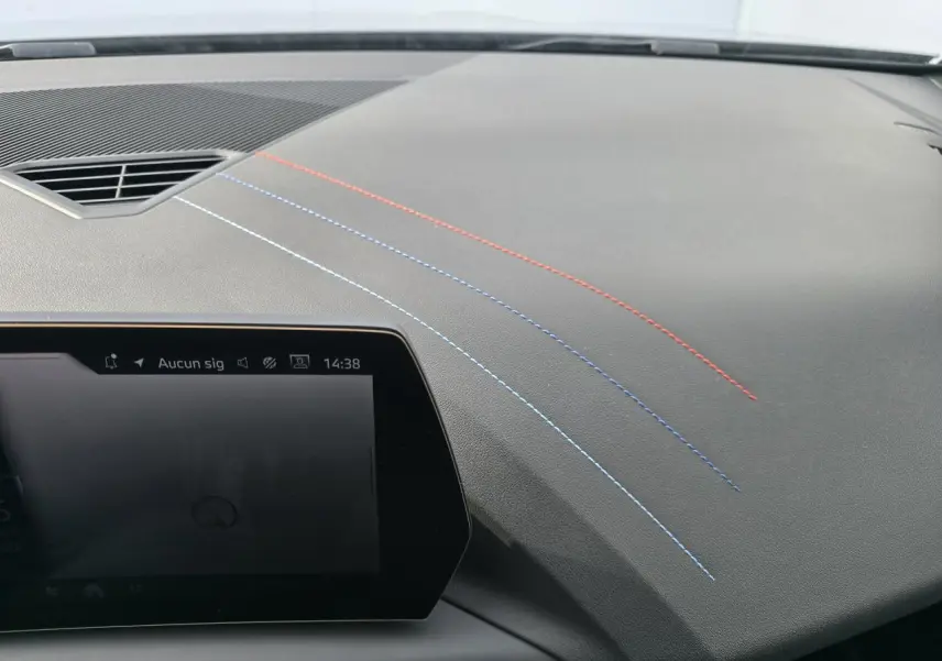 Vue rapprochée du tableau de bord noir avec coutures décoratives tricolores sur BMW Série 1 2025.