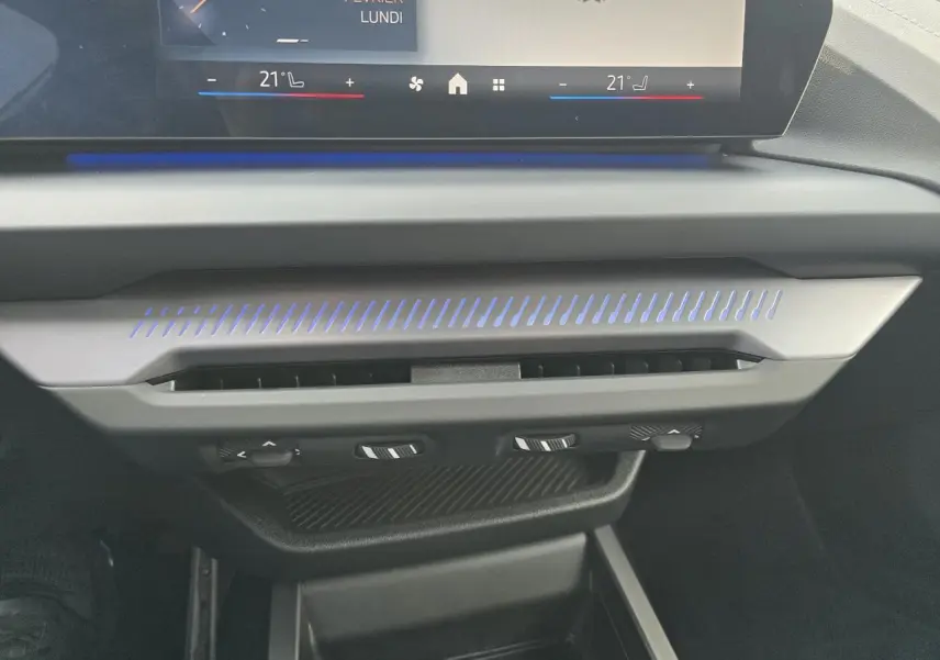 Gros plan sur la console centrale de la BMW Série 1 2025, avec éclairage d'ambiance bleu et commandes de climatisation.