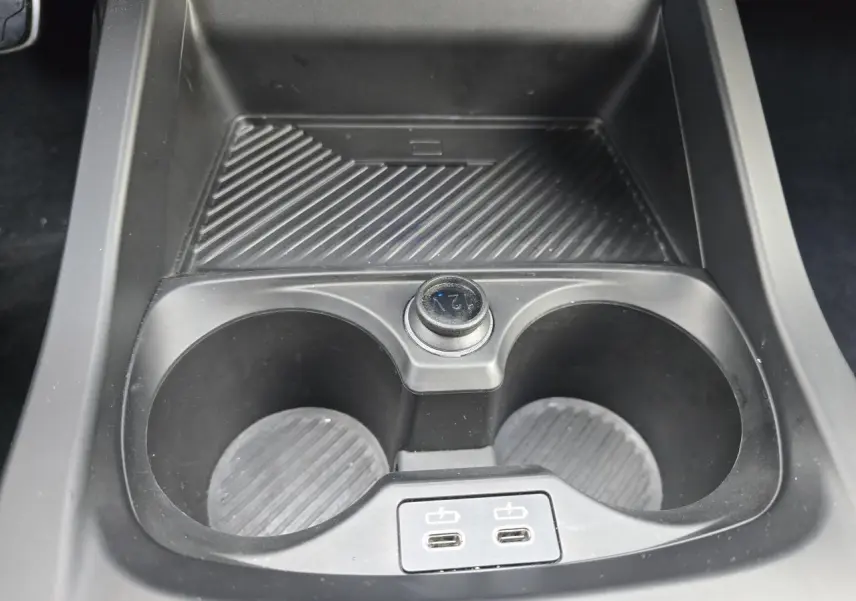 Gros plan sur la console centrale noire de la BMW Série 1 F70 avec porte-gobelets et deux ports USB-C.