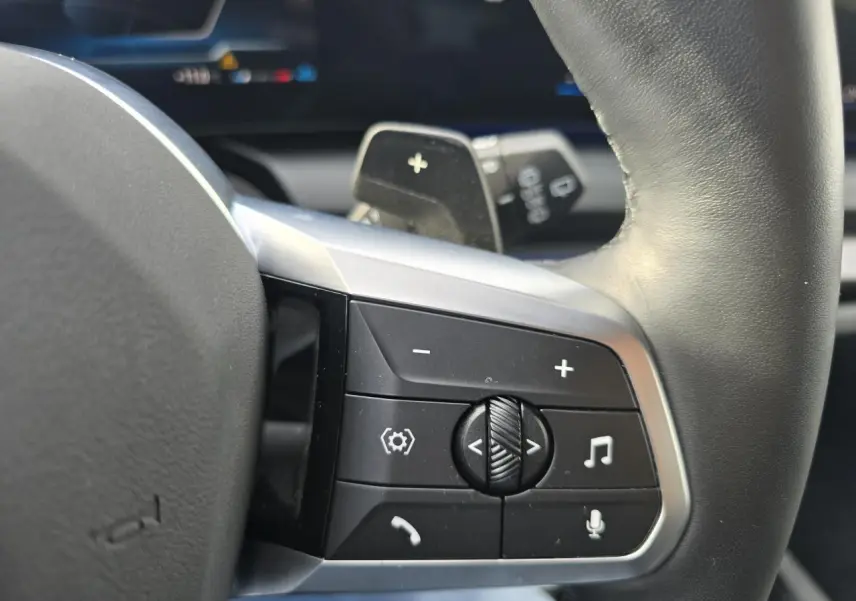 Gros plan sur les commandes au volant cuir noir de la BMW Série 1 F70 120 M Sport avec finition argentée.