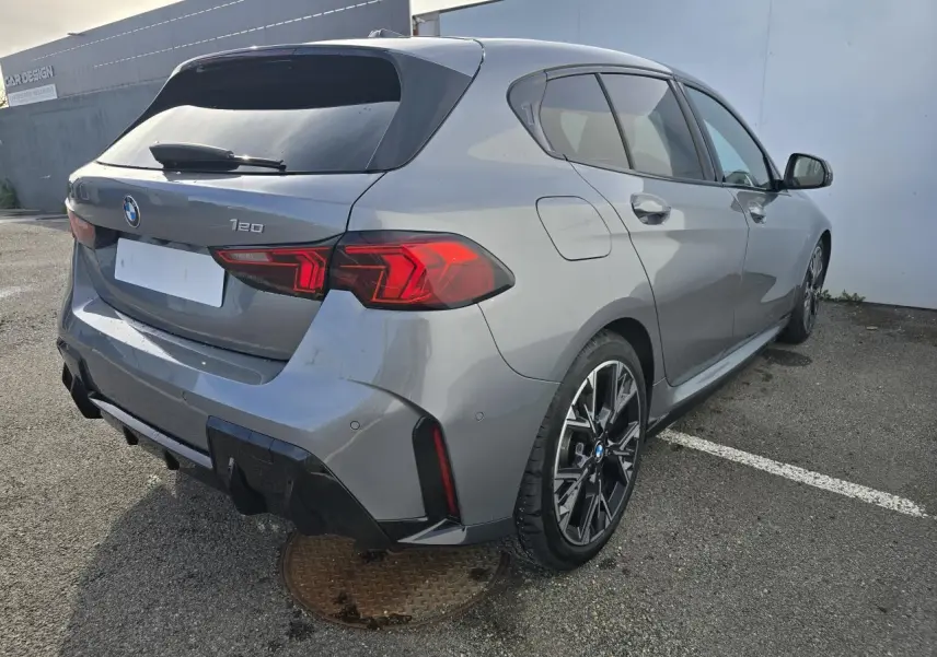 BMW Série 1 gris Skyscraper vue 3/4 arrière droit avec toit noir et jantes M Sport bicolores.
