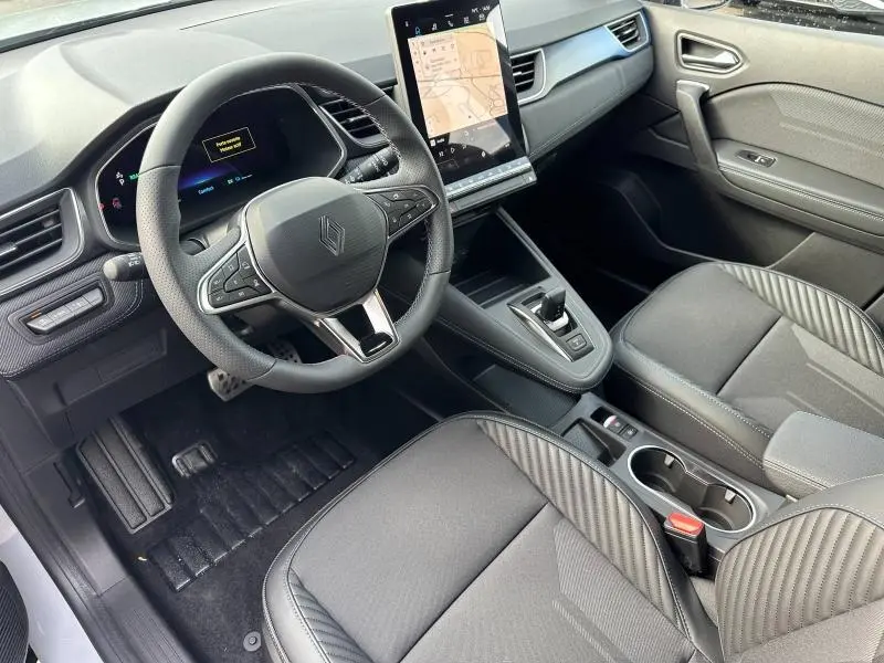 Vue intérieure côté conducteur du Renault Captur 1.8 E-Tech hybride 2026 avec volant multifonction et écran tactile vertical.