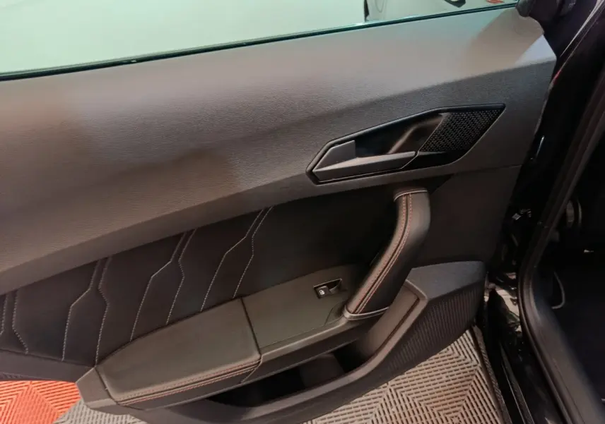 Gros plan sur la porte avant gauche noire du CUPRA Formentor 2024 avec surpiqûres rouges et poignée intégrée.