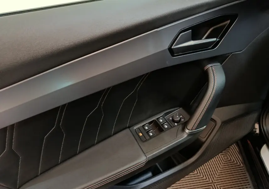 Gros plan sur la porte intérieure côté conducteur du CUPRA Formentor noir, avec surpiqûres et commandes électriques.