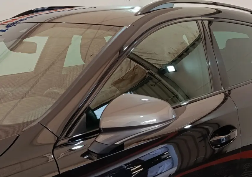 Vue rapprochée du côté gauche noir brillant du CUPRA Formentor 1.4 e-HYBRID avec rétroviseur ton caisse et rails de toit.