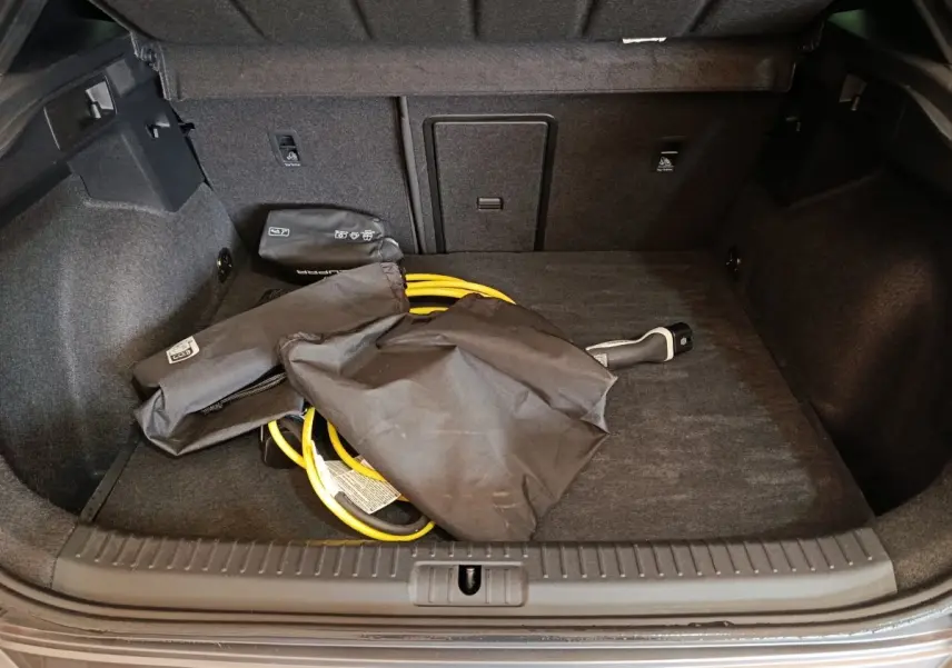 Coffre ouvert d’une CUPRA Formentor noir 2024, montrant le câble de charge hybride rangé au sol.