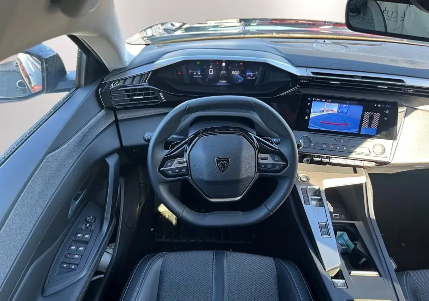 Vue intérieure frontale du poste de conduite noir de la Peugeot 308 1.5 BlueHDi avec écran tactile affichant la caméra de recul.